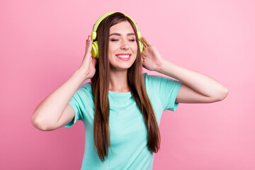 Photo of sweet dreamy young lady wear teal t-shirt smiling arms headphones listening songs isolated pink color background
