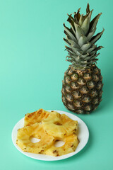 Fototapeta na wymiar Pineapple and plate with grilled slices on mint background