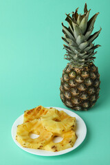 Pineapple and plate with grilled slices on mint background