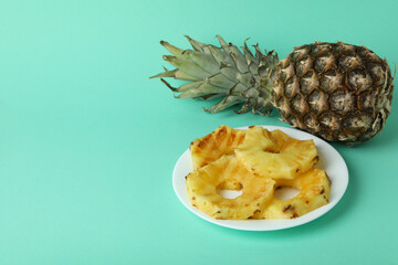 Pineapple and plate with grilled slices on mint background