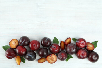 Flat lay composition with plums on white wooden background