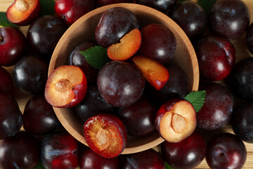 Plums in a wooden bowl on the table, all over  background