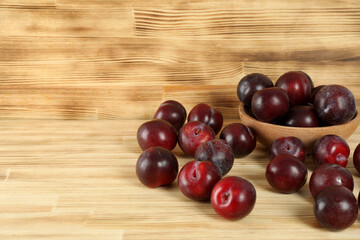 Plums in a wooden bowl on a wooden table