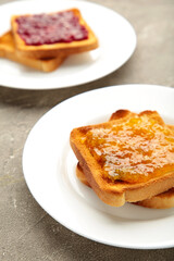 Fresh toast with butter and different jams on grey table. Vertical photo