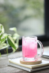 Ice Strawberry juice and notebooks and plants on wooden table in front of window