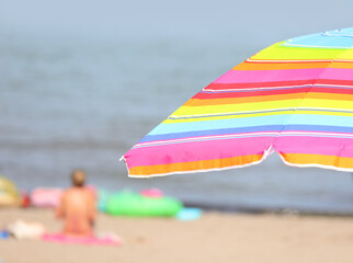 parasol umbrella on the beach with swimmers having fun during the summer holidays