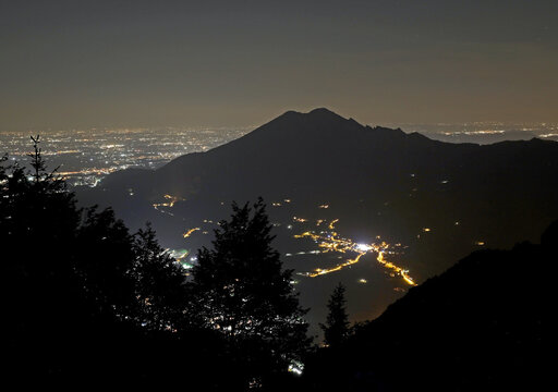 silhouette of Mount Summano near the city of Vicenza in Italy with the city lights in the distant plain