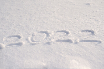 Inscription 2022. Numbers 2022 are written on white snow. Concept of the date of the new year.