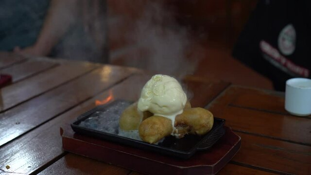 Burning ice cream and fried banana flame lit dessert with alcohol entertaining serving method