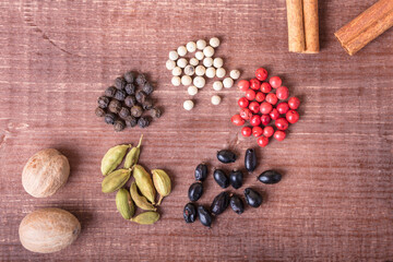 Cardamom, nutmeg, cinnamon and other aromatic spices lie on a wooden table
