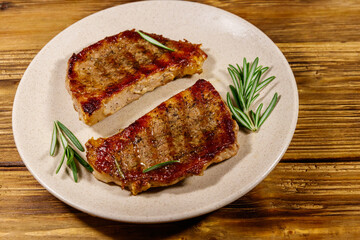 Grilled pork steaks with rosemary on wooden table