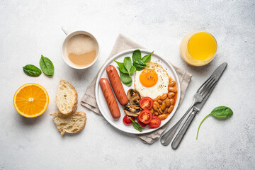 Traditional English breakfast with fried egg, beans in tomato sauce, grilled sausages, mushrooms and fresh tomatoes, served on plate. White background^ flat lay