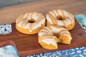 Delicious fresh glazed donuts served on a wooden board.