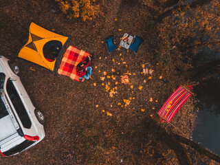 overhead top view of autumn camping site with tent car hammock bonfire