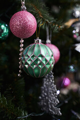Obraz premium Christmas decoration in the form of a green and pink ball on a Christmas tree along with other decorations