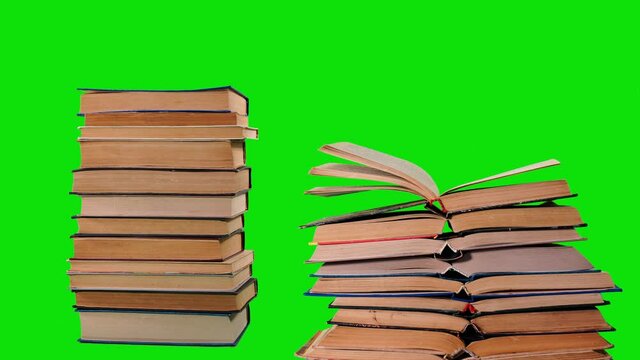 Lots of pile of books growing on green chroma key background. Teaching and learning science concept. A stack of books on a wooden table, stop motion, time laps.