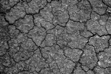 Top view of cracked black and white dry soil ground which is the effect from global warming, natural texture background