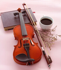 Fototapeta na wymiar Violin and bow put beside White ceramic cup with black coffee,
