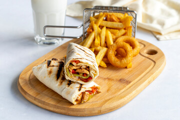 Chicken wrap on a white background. With french fries and onion rings