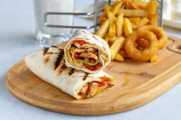Chicken wrap on a white background. With french fries and onion rings