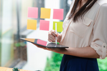 Close-up of a businesswoman hands standing and taking notes using a tablet at the office.