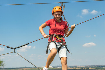 A girl in a sports park on a cable car overcomes obstacles.