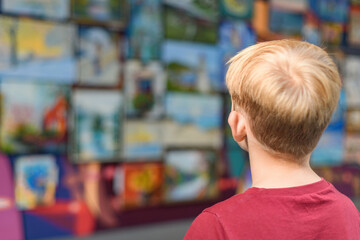 The boy looks at the paintings in the exhibition gallery.