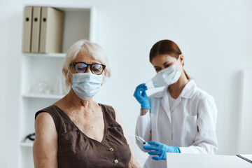 elderly woman wearing a medical mask in the hospital for vaccinations