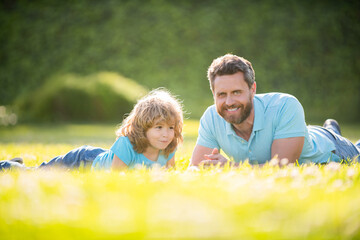 Fototapeta premium happy family of daddy and son kid relax in summer park green grass, fathers day
