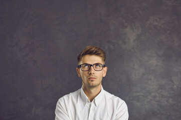 Pensive young Caucasian man on black studio background look up think of promotion offer deal. Millennial male consider sale or discount on empty blank copy space. Advertisement, copyspace.