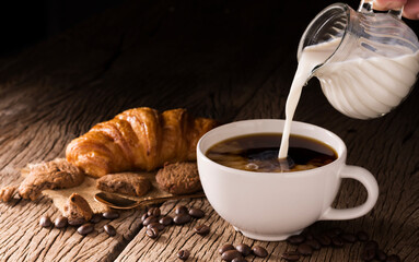 Pour milk into coffee cup on black background