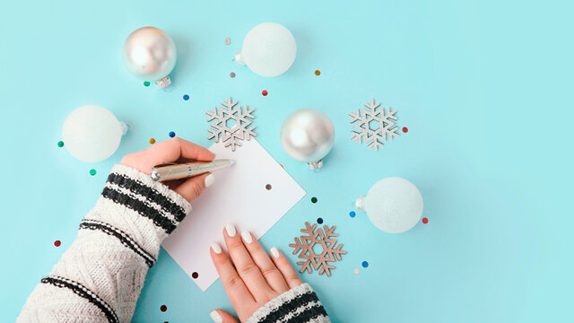 Top view of woman writing on blank greeting card.New year decor around,large banner.