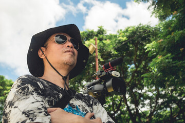 A veteran cameraman on standby with a medium sized camcorder mounted on a tripod.