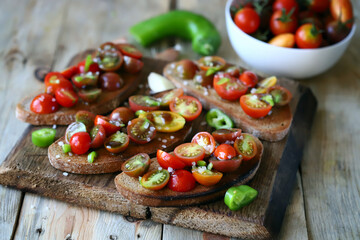 Croutons with cherry tomatoes, garlic and hot peppers. Healthy bruschetta with tomatoes.