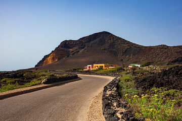 Road with dry stone wall . The Monte Nero Volcano on the background. Linosa