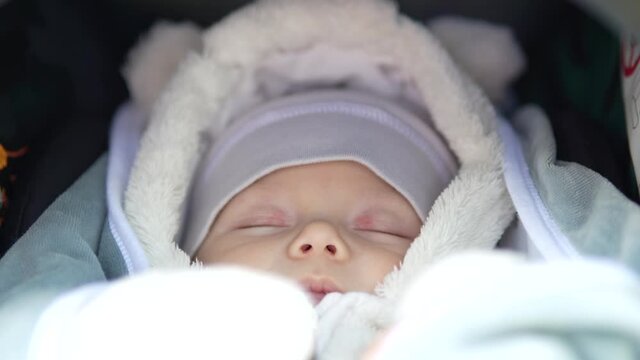 Newborn baby boy sleep in stroller at cold autumn weather in the park