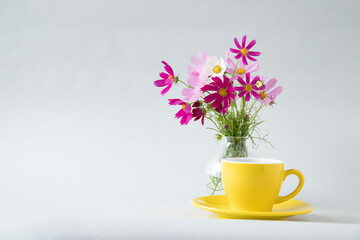 黄色のカップのコーヒーとピンクのコスモス（灰色の背景）