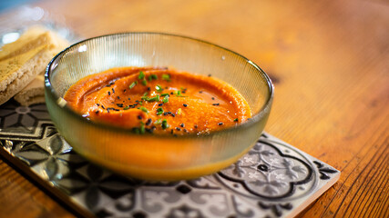 humus with seeds in a bowl on a decorative tile on a wooden surface