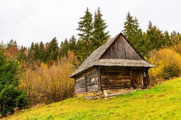 Old house in a small valley with green meadows and colorful forests