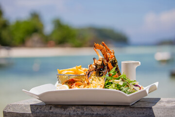 Large lobster steak on a plate against the backdrop of a tropical landscape. Exotic gourmet food by the sea.