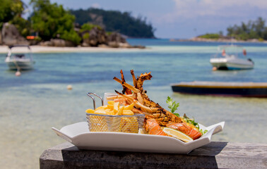 Large lobster steak on a plate against the backdrop of a tropical landscape. Exotic gourmet food by...