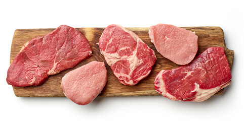 Various types of steak on wooden board isolated on white, from above
