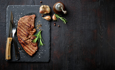 Grilled striploin steak on black stone board; from above