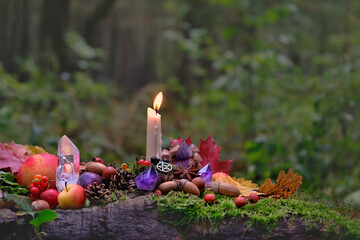 Candle, gemstones, fruits and nuts on natural forest background. magical esoteric ritual. altar for mabon sabbat. Mysticism, divination, wicca, occultism, Witchcraft concept - obrazy, fototapety, plakaty