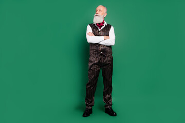 Photo of minded intelligent cool vintage man folded hands look side empty space wear striped suit on green color background