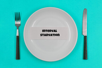 Concept, table setting, empty white plate with fork and knife on blue background, with one of the principles of healthy living - Interval starvation