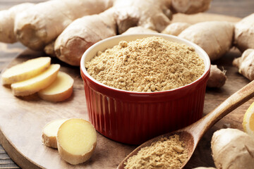 Lots of fresh and grated ginger on a wooden background.