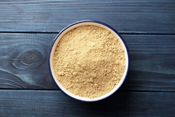 A bowl full of ginger spices on a blue wooden background.
