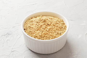 White bowl full of dry ginger on textured background