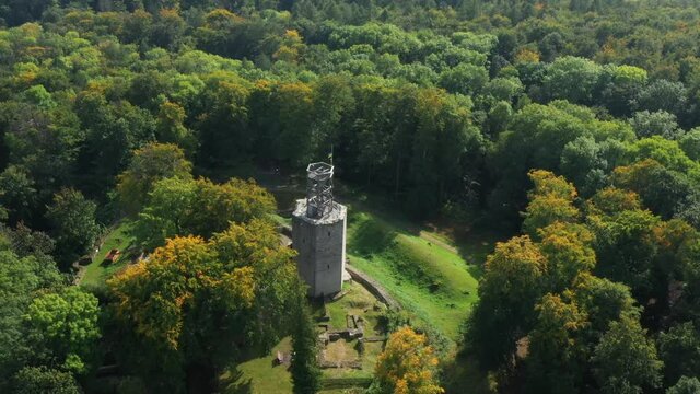 Aerial view with an overview of a dense forest area and a ruined tower from the 12th century with polished defensive walls